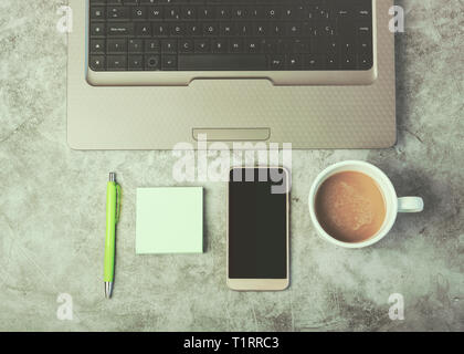 Ordinateur portable, téléphone mobile et tasse de café sur un bureau contre Grunge background Banque D'Images