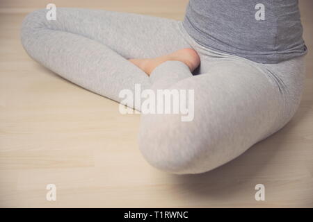 Teen Girl in Turkish Position assise en pantalon sur plancher en bois libre Banque D'Images