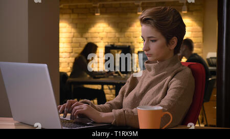 De jeunes pousses closeup portrait of attractive employée de la saisie sur l'ordinateur portable à l'intérieur dans le bureau Banque D'Images