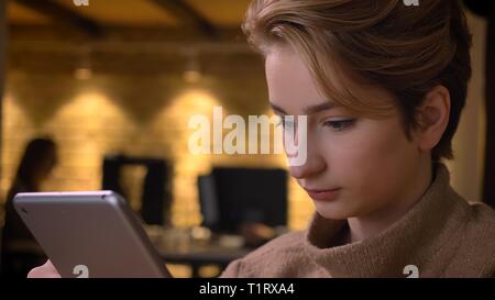 De jeunes pousses Gros plan caucasian businesswoman attrayants à l'aide de la tablette à l'intérieur dans le bureau Banque D'Images