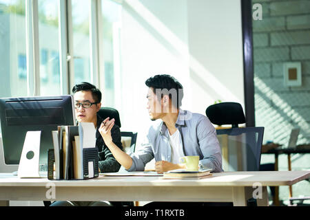 Deux jeunes gens d'affaires asiatiques travaillant ensemble au pouvoir discuter affaires. Banque D'Images