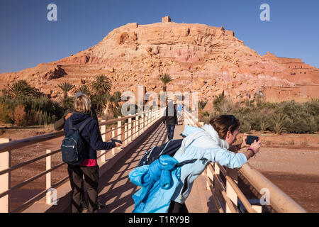 Un pont plein de touristes menant au cours de l'Asif Ounila River à l'égard du Ksar Aït-Ben-Haddou, Aït Benhaddou‌, Province de Ouarzazate, Maroc. Banque D'Images