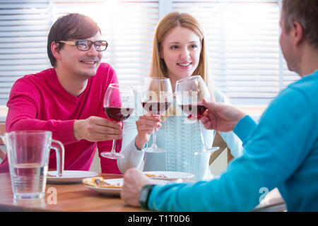Groupe de jeunes Qui Profitent De Repas et de vin au restaurant. Amis dîner, célébration et s'accrocher. Toaster les mains. Banque D'Images