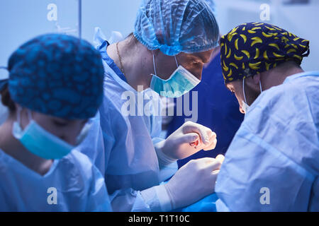 Chirurgiens sérieux durant une opération chirurgicale à l'hôpital. Traitement croisé Banque D'Images
