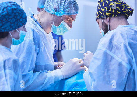 Chirurgiens sérieux durant une opération chirurgicale à l'hôpital. Traitement croisé Banque D'Images
