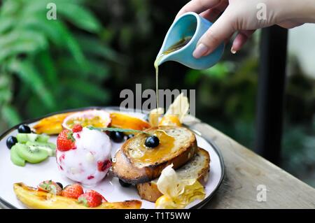 Verser un peu de miel à la crème glacée aux fruits petits fruits et pain grillé Banque D'Images