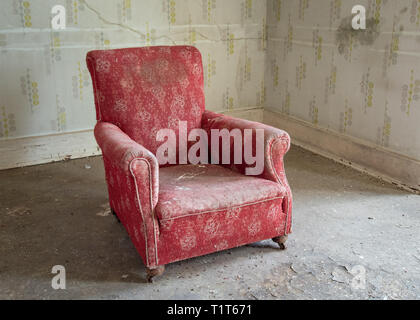 Un vieux fauteuil rouge abandonné et couvert de poussière s'élève dans un désert depuis longtemps les patients prix dans le reste de l'asile Sunnyside, Montrose, Angus Banque D'Images