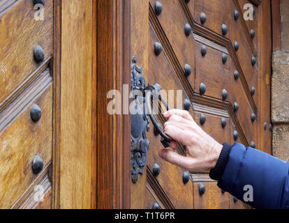 L'homme détient ou poignée de porte de heurtoir de porte en bois ancien. Il ouvre la porte verrouillée. Banque D'Images