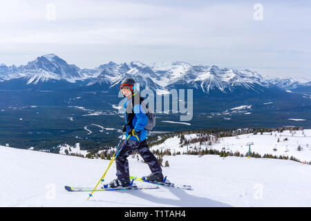 Jeune skieur debout au bord d'une chaîne de montagnes dans le lac Louise au les Rocheuses canadiennes de l'Alberta, Canada. Banque D'Images