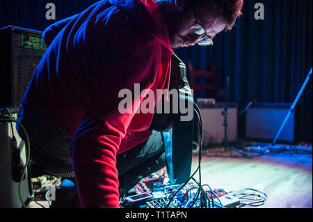 Un homme joue de la musique expérimentale avec une guitare et une multitude d'effets transformateurs, au cours d'une performance solo. Banque D'Images