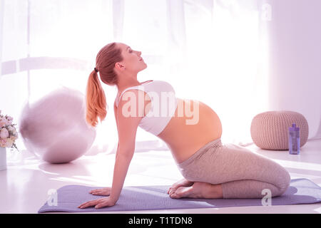 En utilisant la fonction de Jeune femme enceinte à poil long dans un t-shirt blanc la pratique du yoga Banque D'Images