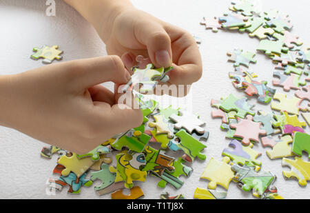 Close up of les mains de l'enfant jouer avec des puzzles sur table lumineuse. Au début de l'apprentissage. fond de rayure de jouets éducatifs Banque D'Images