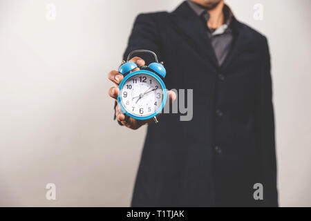 La section basse de un homme vêtu d'un costume et tenant une horloge vintage Banque D'Images