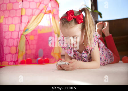 Jeune fille l'écoute de musique au casque à partir d'un smartphone dans un environnement d'accueil Banque D'Images