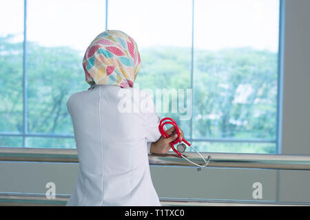 Dos d'une femme médecin face à la fenêtre, en pensant à quelque chose Banque D'Images