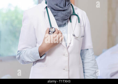 Vue de face corps du hijab médecin femme stetoschope tenir la main à l'intérieur d'une chambre lit d'hôpital Banque D'Images