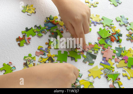 Close up of les mains de l'enfant jouer avec des puzzles sur table lumineuse. Au début de l'apprentissage. enfant joue puzzles Banque D'Images