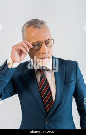 Mature businessman touching verres alors qu'il se trouvait isolé sur gray Banque D'Images