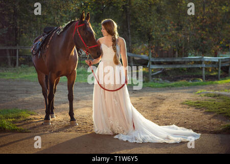 Les jeunes à bride sa grange avec son cheval arabe Banque D'Images