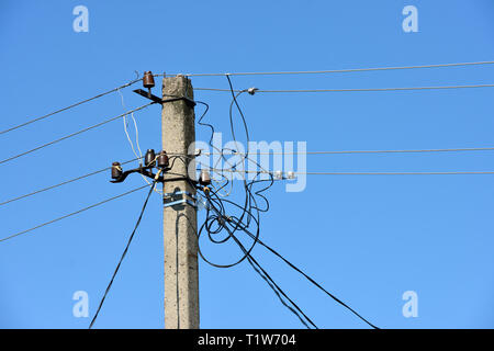 Close-up partie supérieure du poteau avec beaucoup de fils électriques et les isolants dans la lumière du soleil du matin lumineux bleu sur fond de ciel clair. Banque D'Images