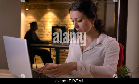 De jeunes pousses Gros plan pretty caucasian businesswoman typing sur l'ordinateur portable à l'intérieur sur le lieu de travail Banque D'Images