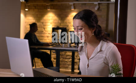 De jeunes pousses Gros plan femme assez bien réussi à taper sur l'ordinateur portable et d'obtenir une assurance l'accomplissement intérieur sur le lieu de travail Banque D'Images