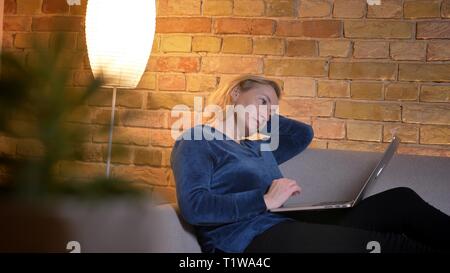 Portrait de femme de race blanche de travail avec ordinateur portable et de lassitude s'appuyant sur la main dans une atmosphère cosy home. Banque D'Images