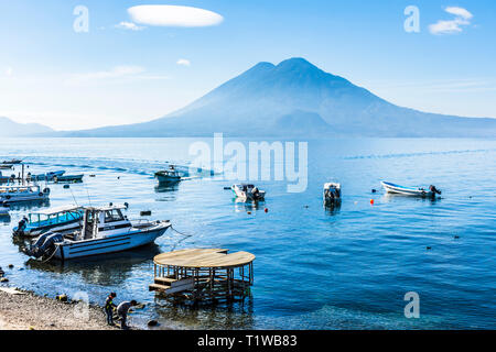 Panajachel, Lac Atitlan, Guatemala - 23 décembre 2018 : bateaux amarrés et plage avec volcans Toliman et Atitlan derrière à Panajachel sur le lac Atitlan. Banque D'Images