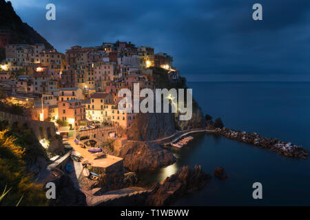 La vue étonnante de Manarola city à la lumière du soir avec les roches de la côte sur un premier plan. Parc National des Cinque Terre, Ligurie, Italie, Europe Banque D'Images