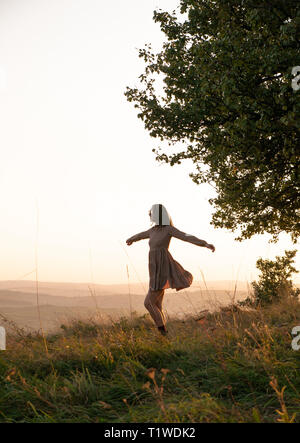 Silhouette d'une jeune fille au coucher du soleil sur un fond de la ville. Jolie fille se sentir heureux. Banque D'Images