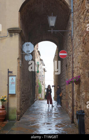 Pienza/Italie - 05/05/18 : deux femmes de se cacher de la pluie dans le cadre de l'ancienne arche de Pienza, l'une des plus belles vieilles villes en Toscane, Italie Banque D'Images