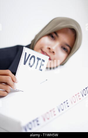 Hijab fille mettre un bulletin dans une urne Banque D'Images