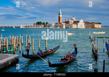 Venise, Italie - 27 juin 2018 : Gondolier de touristes en gondole en lagune de Venise par Saint Marc (San Marco) carré avec San Giorgio di Maggiore ch Banque D'Images