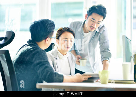 Trois jeunes dirigeants d'Asie qui travaillent ensemble à discuter du plan d'office. Banque D'Images