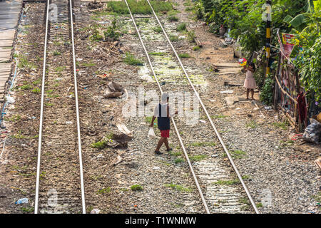 Un garçon marche à une fille de fer de passage à Bangkok, Thaïlande Banque D'Images