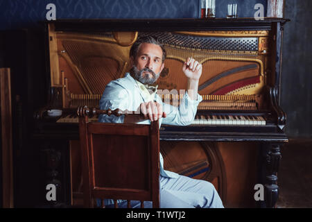 L'homme brutal, avec une barbe de 40 ans joue le vieux piano. Banque D'Images
