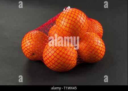 Les oranges en sac mesh sur fond sombre Banque D'Images