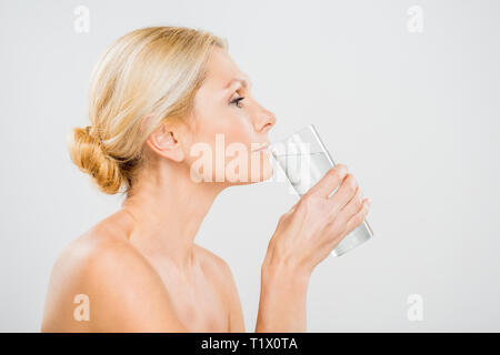 Vue latérale de l'eau potable à partir de la femme mature verre isolé sur gris Banque D'Images