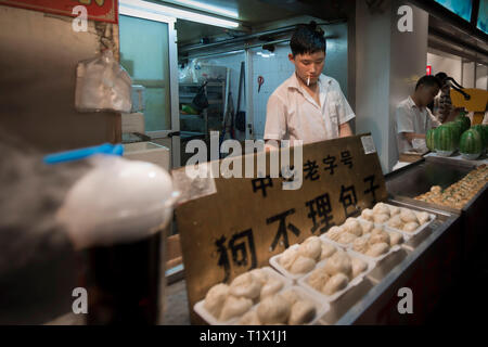 La rue Wangfujing, Beijing, Chine - 0802 2016 : un chinois fumeurs et la préparation de boulettes en rue Wangfujing, une rue commerçante de Beijing, Chine Banque D'Images