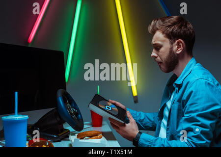 Vue latérale du beau et bon-looking man holding compact disque avec jeu vidéo Banque D'Images