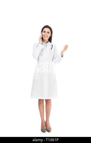 Sur toute la longueur d'un médecin en blouse blanche avec stéthoscope parle sur smartphone isolated on white Banque D'Images