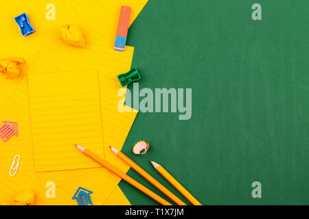 La papeterie scolaire et orange feuille de papier se trouvent sur la green school board formant un cadre de texte. près de crayon et de pages froissées. La télévision l'espace de copie Banque D'Images