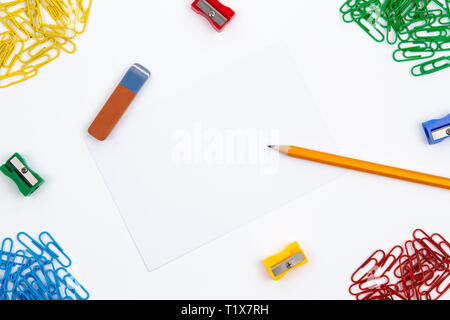 Crayon, gomme, taille-crayons, trombones se situent dans différents angles de la feuille sur un fond blanc. L'image de héros et copy space Banque D'Images