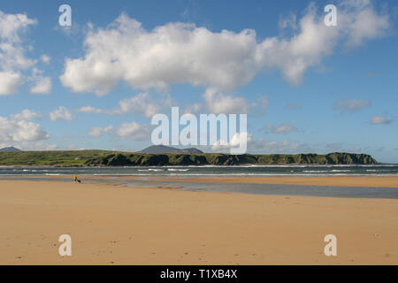 Femme avec chien sur une plage de sable à cinq doigts Strand sur une journée ensoleillée sur la péninsule d'Inishowen. Banque D'Images