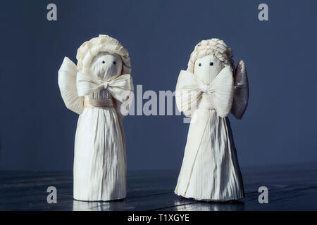 Deux anges de la cosse de maïs artisanal figurines standing sur table en bois fissuré, tons noir minuit, faites-le vous-même, le projet d'artisanat, le christianisme, l'étonnante Banque D'Images