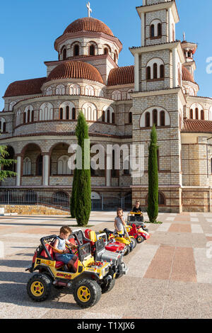 Les enfants jouant sur les voitures miniatures en face de la cathédrale orthodoxe de Korca, Korca, sud-est de l'Albanie. Banque D'Images