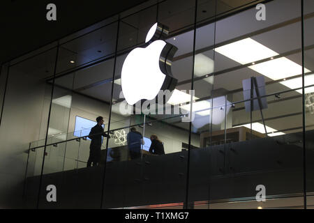 Façade en verre d'Apple Store avec logo de pomme la nuit.Les clients et le personnel à l'intérieur du magasin de pommes.Par prise de vue de nuit. Banque D'Images