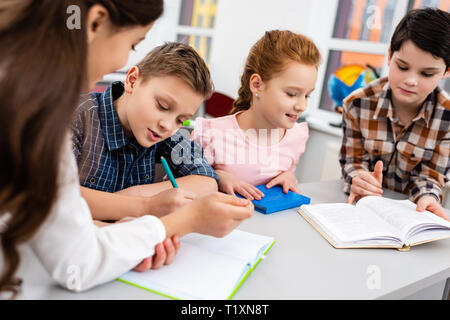 4 élèves avec ordinateur portable et books at desk in classroom Banque D'Images