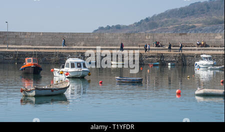 Lyme Regis, dans le Dorset, UK. 29 mars 2019. Météo France : Un autre jour de soleil et un ciel bleu lumineux que la station balnéaire ville de Lyme Regis comme la canicule au début du printemps se poursuit. Les visiteurs marchent le long du port de Cobb dans le soleil. Credit : Celia McMahon/Alamy Live News Banque D'Images