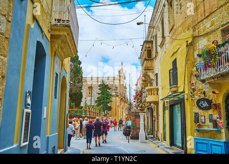 RABAT, MALTE - 16 juin 2018 : La foule de touristes à St Paul Street avec de nombreux cafés, bars, magasins de souvenirs et St Paul l'église paroissiale sur le backg Banque D'Images